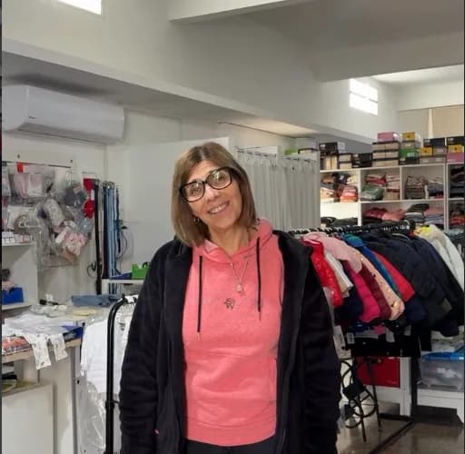 Rosana Pellarolo sonriendo dentro de su local, Bambino's, entre percheros con ropa y estantes con mercadería.
